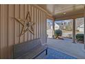 Inviting covered front porch with an exterior star decoration, bench, and blue outdoor rug at 5719 Sierra Bend Way, Hoschton, GA 30548