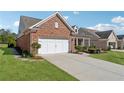 Side view of a brick home showing a two-car garage and manicured lawn at 2975 Thistle Trl, Suwanee, GA 30024