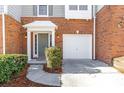 Townhome exterior featuring a one-car garage, manicured bushes, and covered entrance at 4000 Howell Park Rd, Duluth, GA 30096