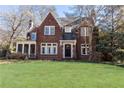 Charming brick home with a well-manicured lawn and mature trees and a screen in porch to the side at 57 Rumson Ne Way, Atlanta, GA 30305