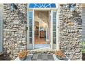 Elegant stone entryway with sidelights, transom window, and glimpses of the foyer's staircase at 4125 Bridle Ridge Dr, Suwanee, GA 30024
