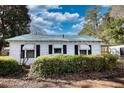 Charming home featuring mature landscaping, dark shutters, and a tin roof at 5500 Rockbridge Road, Stone Mountain, GA 30088