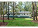 View of the home's exterior and backyard featuring a manicured lawn and bordered by mature trees at 3345 Flowers Dr, Atlanta, GA 30337