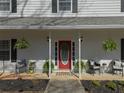 Close-up of a welcoming front porch with a red door, hanging ferns, and comfortable seating area at 4260 Laurel Glen Ct, Douglasville, GA 30135