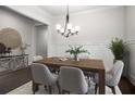 Elegant dining room with a modern chandelier, wainscoting, and a wooden table set for six at 628 Avondale Hills Dr, Decatur, GA 30032
