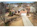 Aerial view of a brick two-story home with lush landscaping, mature trees, and a long driveway at 2520 Cross Springs Dr, Cumming, GA 30041