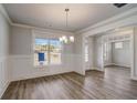 Dining room with wainscoting, wood floors, modern light fixture, and natural light at 3870 Ivy Cottage Dr, Snellville, GA 30039