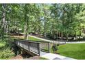 Scenic view of property featuring a bridge leading to the home, surrounded by lush greenery and mature trees at 95 Lakeshore Ne Cir, Marietta, GA 30067