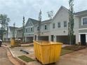 Street view of new townhomes with landscaping, open garages, and yellow container in the street at 121 Priestwood Ln, Acworth, GA 30102
