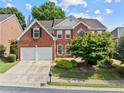Charming brick home with a two-car garage, a manicured lawn and mature landscaping at 4831 Edinburgh Dr, Smyrna, GA 30082
