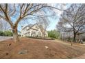 View of an elegant home with manicured lawns, situated on a lush green hillside at 5825 Laurel Oak Dr, Suwanee, GA 30024