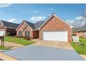 Beautiful single-story brick home with a well-maintained lawn, attached garage and a blue brick paver driveway at 219 Prominent Loop, Mcdonough, GA 30253
