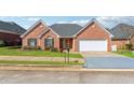 Charming single-story brick home featuring an attached two-car garage, well-manicured lawn, and a welcoming entryway at 219 Prominent Loop, Mcdonough, GA 30253