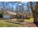 Single-story home featuring stone accents, a two-car garage, an American flag, and landscaping at 145 Alcovy Cir, Covington, GA 30014