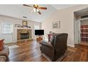 Cozy living room featuring a stone fireplace, ceiling fan, hardwood floors, and ample natural light at 145 Alcovy Cir, Covington, GA 30014