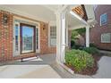 Inviting front porch with brick facade, decorative glass door, and manicured shrubbery at 2528 Picket Fence Ln, Snellville, GA 30078