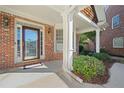 Inviting front porch with brick siding, decorative door, and manicured landscaping at 2528 Picket Fence Ln, Snellville, GA 30078