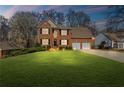 Charming two-story red brick home featuring a manicured lawn, black shutters and a two car garage at 1760 Clayton Cir, Cumming, GA 30040