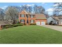 Charming two-story red brick home featuring a manicured lawn, black shutters and a two car garage at 1760 Clayton Cir, Cumming, GA 30040