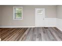 Bright room with modern flooring, wainscoting, a window with grill, and a white door at 16 Wadley Nw St, Atlanta, GA 30314