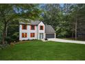 Attractive two-story home with attached two-car garage, gray roof and surrounding trees and lush green lawn at 1920 Rocky Mill Ln, Lawrenceville, GA 30044