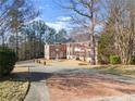 Brick home with well-maintained grounds, circular driveway, and a charming fountain centerpiece at 10 Club Ct, Alpharetta, GA 30005