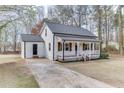 Angle view of a charming home with a covered front porch, gray roof, long driveway, and white siding at 2737 King Arthur Ct, Buford, GA 30519