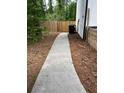 View of the backyard with a concrete walkway and surrounding greenery, creating a serene outdoor space at 3042 Humphries Hill Rd, Austell, GA 30106