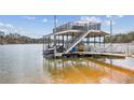 View of a lakeside boat dock featuring a covered lift, second story deck and stairway at 8 Colonial Club Se Dr, Acworth, GA 30102