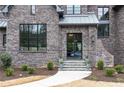 Inviting front entrance featuring a brick facade, black framed windows, and stone steps with manicured landscaping at 3338 Breton Ne Cir, Brookhaven, GA 30319