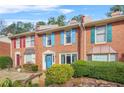 A brick townhome showcasing colorful shutters, a bright blue door with wreath, and lush front yard landscaping at 6105 Queen Anne Ct, Norcross, GA 30093