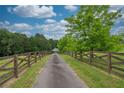 Long, paved driveway lined with rustic wooden fencing and vibrant greenery leading to the property at 3285 Kelly Glen Ct, Dacula, GA 30019