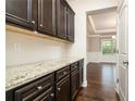 Butler's pantry featuring granite countertops and dark cabinets at 211 Lotus Ln, Covington, GA 30016