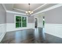 Dining room with hardwood floors, decorative wainscoting, modern lighting, and a large window with views of the backyard at 3118 Old Covington Hwy, Covington, GA 30014