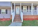 Split-level home featuring a gray exterior, a driveway, and a covered front porch with railing at 4185 Duesenberg Dr, Tucker, GA 30084