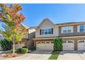 Well-maintained townhome featuring brick accents, two-car garage, and mature landscaping in front at 2297 Elmbridge Rd, Buford, GA 30519