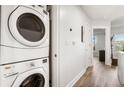 Stackable washer and dryer in laundry area of hallway, with white walls and view to living room at 200 River Vista Dr # 502, Atlanta, GA 30339