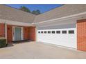 Attached two-car garage with a light blue front door and a red brick wall at 223 Ivy Creek Dr, Loganville, GA 30052