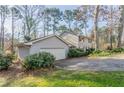 View of the home and attached garage, surrounded by lush greenery and a well-kept lawn at 4641 Waterford Ct, Atlanta, GA 30338