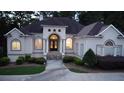 Inviting single-story home with a beige facade, featuring a well-lit entrance and manicured landscaping in the twilight at 433 Abbey Springs Way, Mcdonough, GA 30253