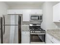 This kitchen includes stainless steel appliances, granite countertops, and white cabinetry at 3164 Robin Rd, Decatur, GA 30032