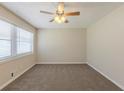 Neutral-toned bedroom with plush carpeting, a ceiling fan, and a large window allowing ample sunlight at 3465 Tulip Dr, Decatur, GA 30032