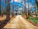 Exterior view of a home showcasing a long driveway lined with trees, leading to the front of the house at 45 Side Trail, Covington, GA 30016