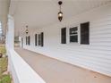 Long front porch with black shutters, white railings and vintage style light fixtures at 3121 Cox Cemetery Rd, Social Circle, GA 30025