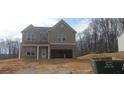 Two-story home featuring a gray exterior, brick accents, and an open two-car garage at 6005 Spring Way, Stonecrest, GA 30038