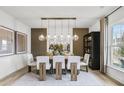 Elegant dining room with modern lighting, wood accent wall, and seating for six, perfect for entertaining at 221 Kindness Cir, Mcdonough, GA 30252