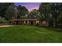 Charming brick home with an attached covered carport, illuminated by warm light during dusk, surrounded by mature trees at 422 Derbyshire Dr, Stone Mountain, GA 30088