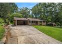 A well maintained home featuring a brick facade, a covered carport, a long driveway, and a green lawn at 422 Derbyshire Dr, Stone Mountain, GA 30088