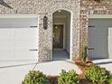 Home's inviting brick facade with a charming arched entryway and two-car garage at 4655 Larkfield Way, Powder Springs, GA 30127