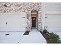 Brick townhome showing garage and front door with address number 689 and small bushes at 4667 Larkfield Way, Powder Springs, GA 30127
